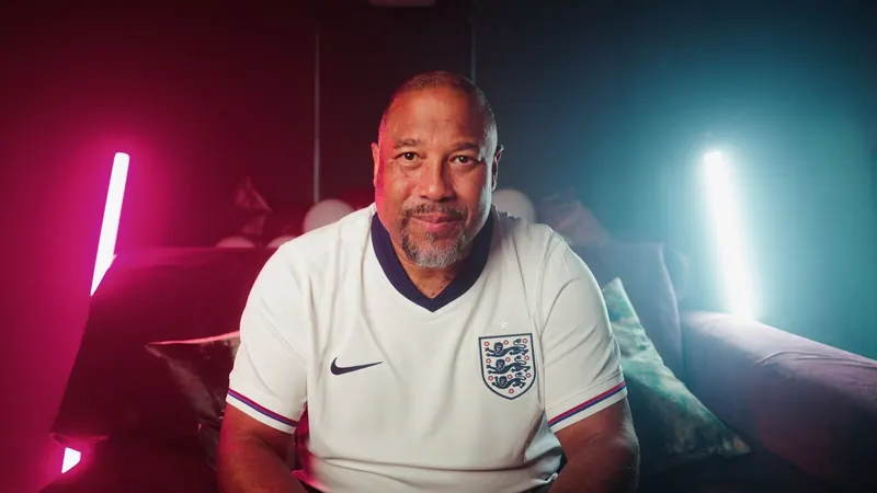 John Barnes in an England shirt, lit in pink and teal.