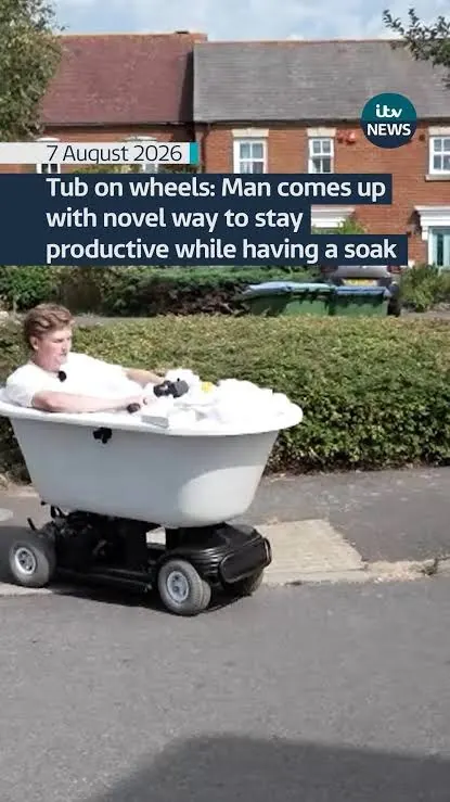 ITV News frame: Will in a white bathtub on a motorised base, driving down a residential street. Caption: Tub on wheels.