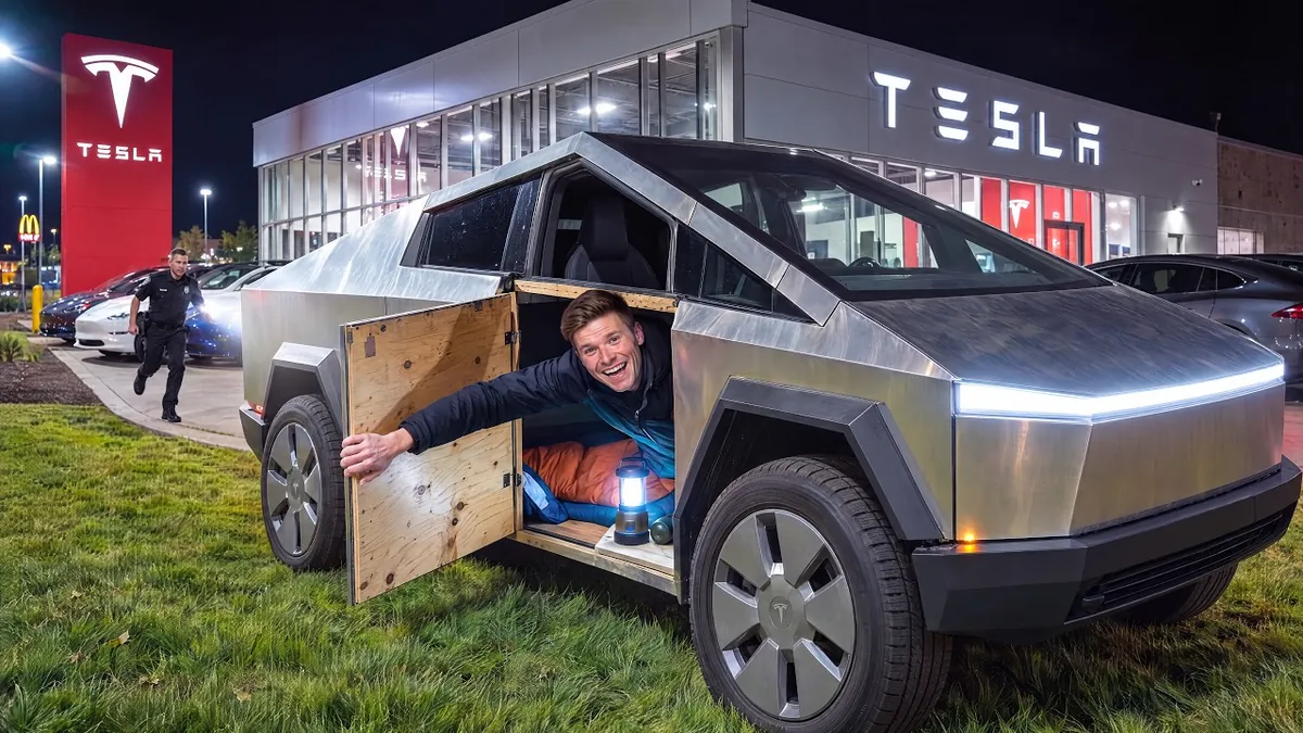 Will leaning out of a hatch in his homemade Cybertruck, parked outside a Tesla showroom at night.