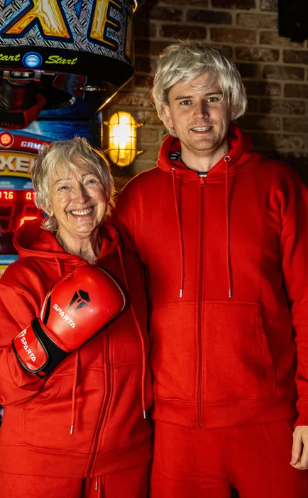 Will in the stunt double's wig and red tracksuit, next to the granny in a boxing glove.