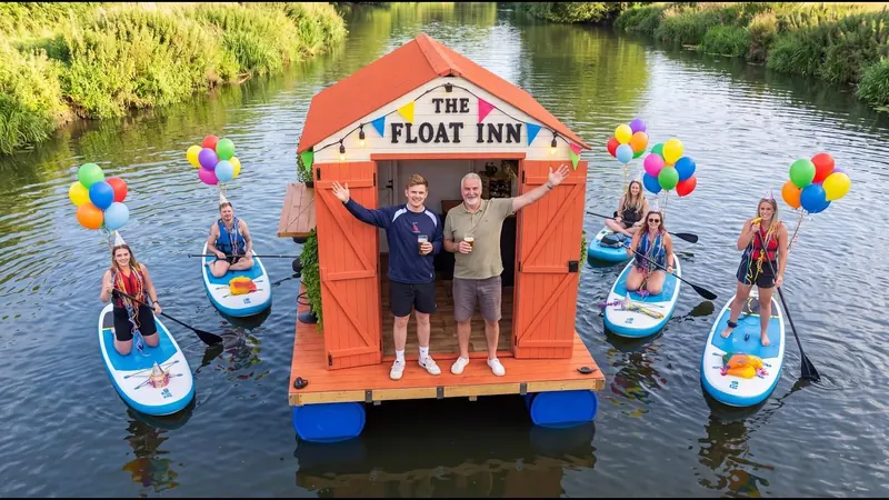 The Float Inn on the river, with friends on paddleboards and balloons tied to the boards.