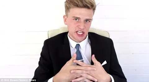 Will in a suit and tie at a desk, in character as David Brent.