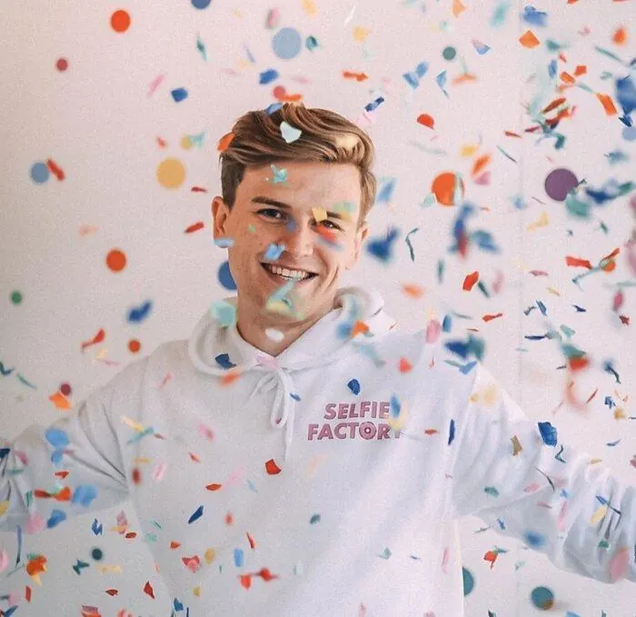 Will in a Selfie Factory hoodie, with confetti in the air.