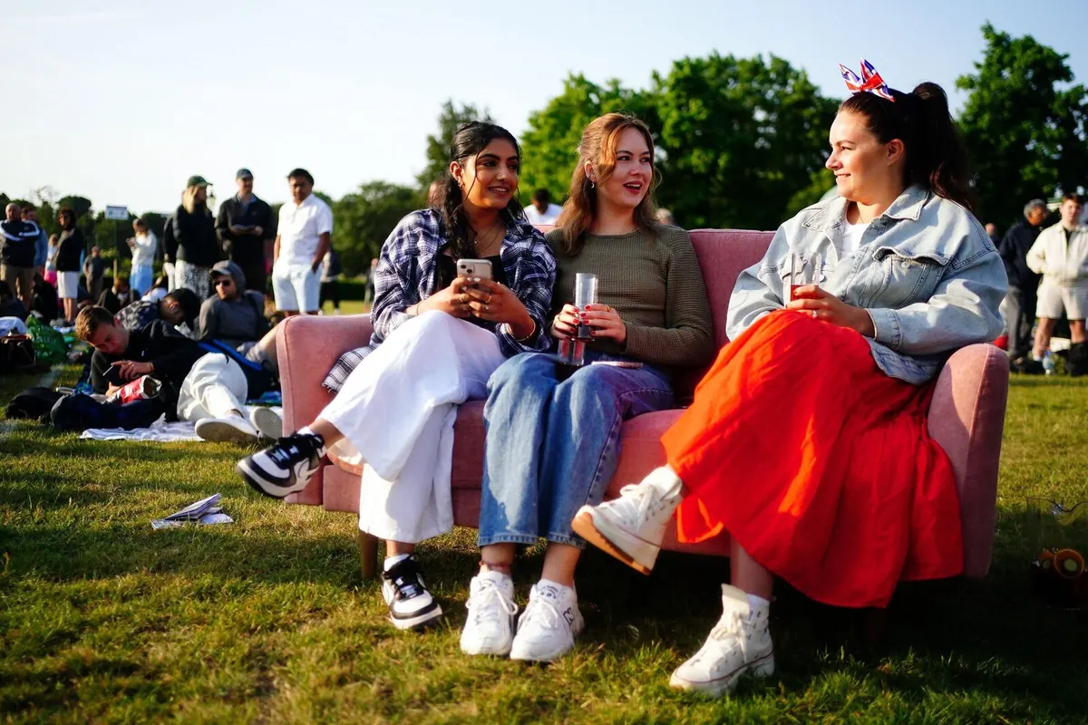 A bright pink Snug sofa among the tents in the Wimbledon ticket queue, with people sitting on it.