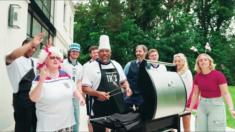 John Barnes at the barbecue in a THIS apron, with fans in England shirts.