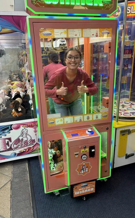 The character inside an arcade claw machine, giving two thumbs up.
